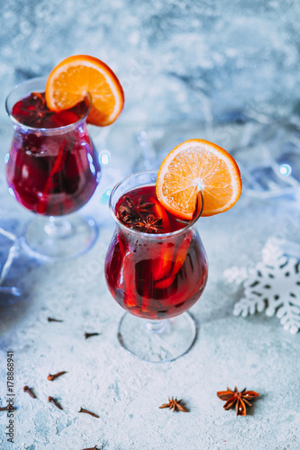 christmas hot mulled wine with spices, candle and traditional New Year decorations and orange on light background