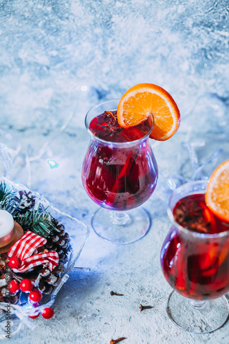 christmas hot mulled wine with spices, candle and traditional New Year decorations and orange on light background