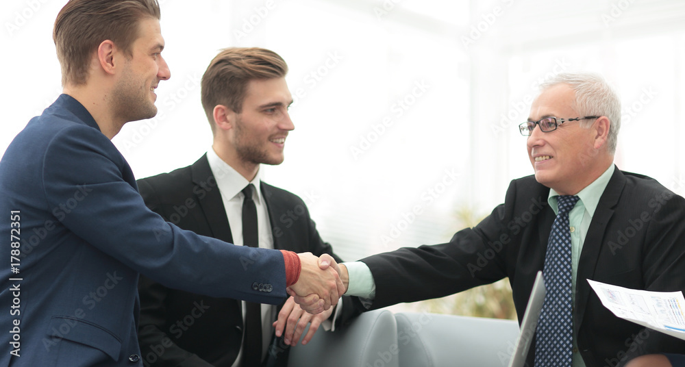 Partners concluding deal and shaking hands in the presence of team members Partners concluding deal and shaking hands in the presence of team members