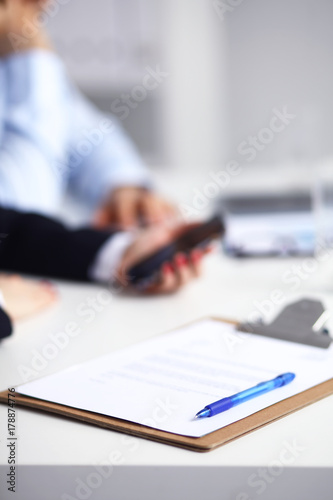 Businesswoman using her phone in office sitting on desk, selective focus