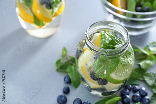 Jar of infused water with fruits and berries on table