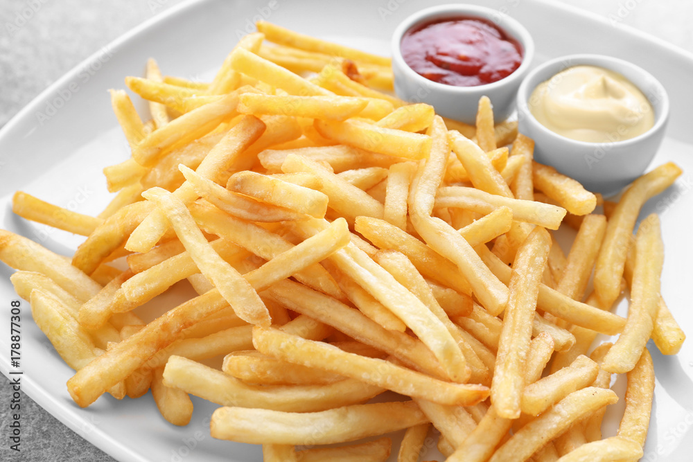 Plate with yummy french fries and sauces in small bowls on table Plate with yummy french fries and sauces in small bowls on table