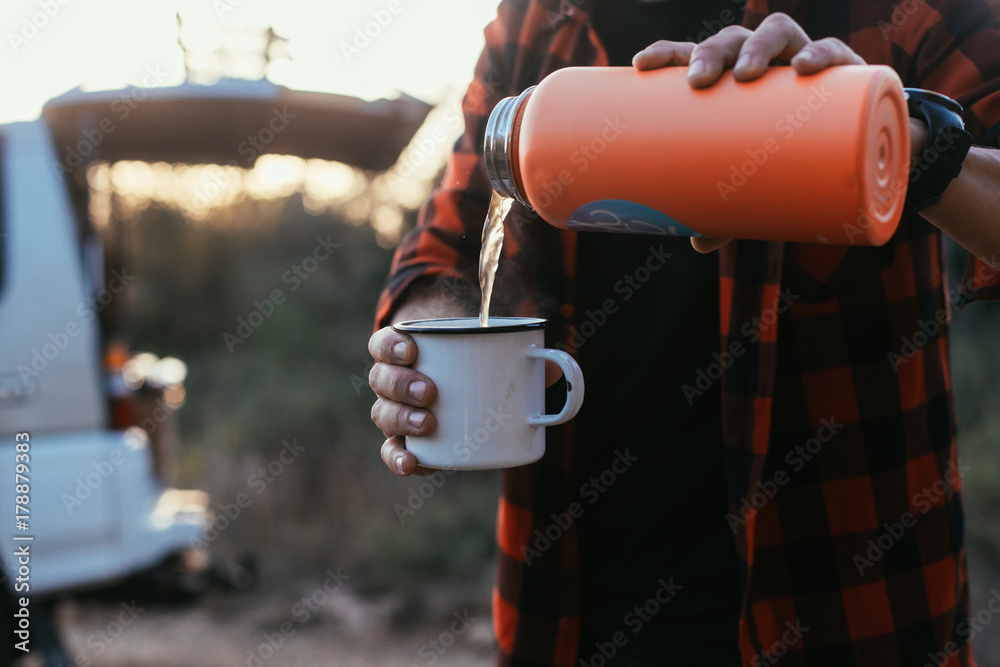 Close up of man or woman pouring hot liquid of tea or coffee from thermos  flask