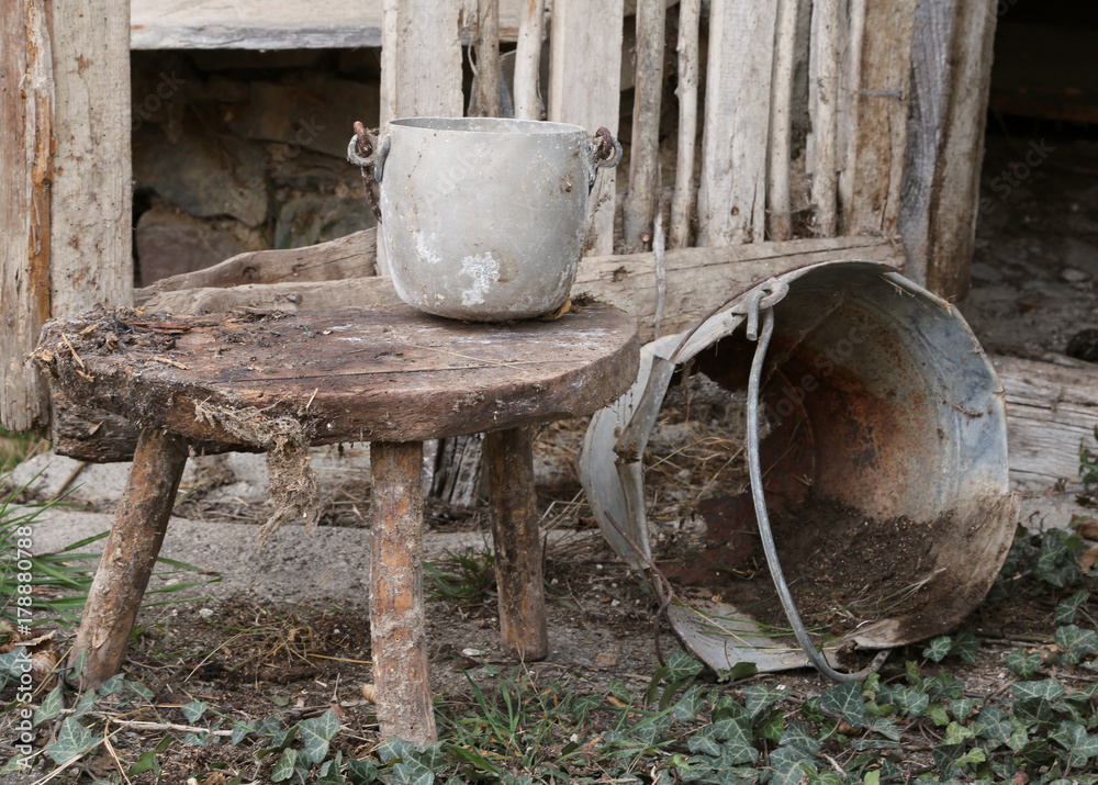 old broken tin bucket and an aluminum pot over the stool old broken tin bucket and an aluminum pot over the stool