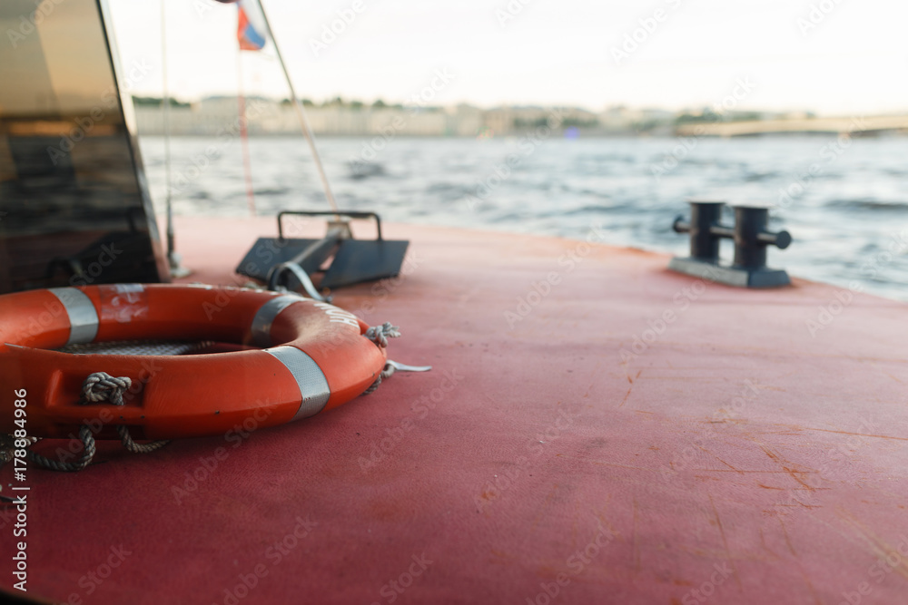 Obraz premium Life preserver on deck. Mount suitable for mooring the vessel on the background of the river surrounded by the city and bridges.
