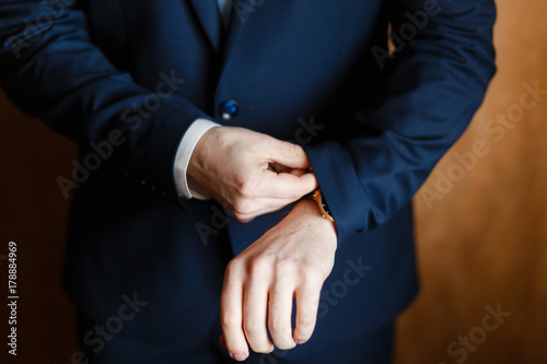 Handsome stylish man dressed in modern formal clothes jacket. Close up of hands of guy in blue jacket, white shirt. Person ready for wedding celebration, graduation or business meeting. Closeup