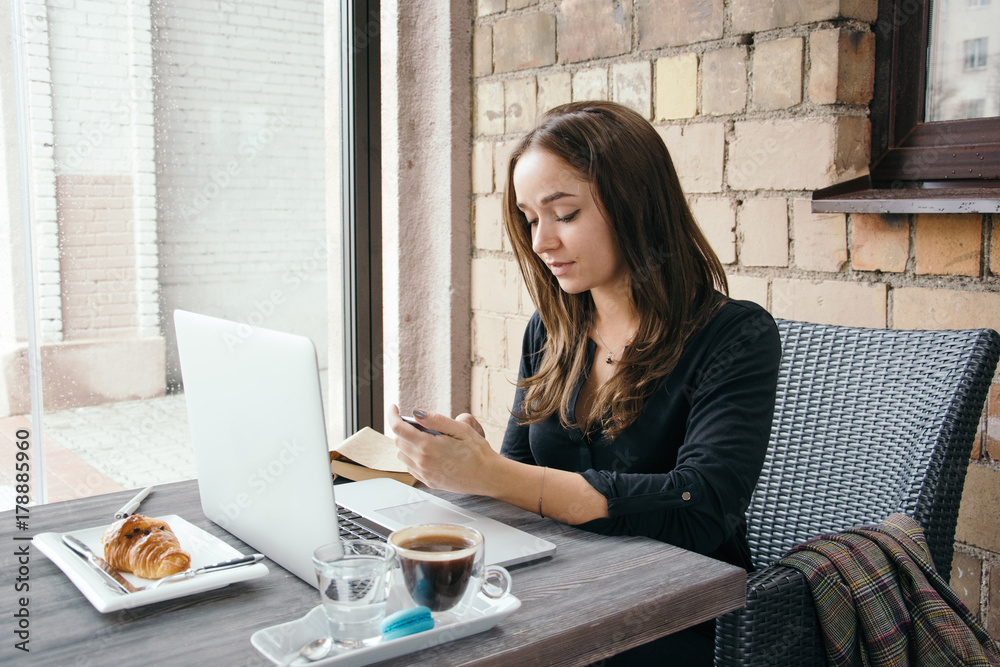 Young attractive woman sitting in a cafe in the morning before her work and planning tasks for the whole day. Beautiful lady talking on the phone and discussing business strategies with her colleague. Young attractive woman sitting in a cafe in the morning before her work and planning tasks for the whole day. Beautiful lady talking on the phone and discussing business strategies with her colleague.