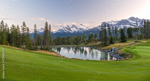 Silvertip Golf Course Green and Distant Landscape View of Three Sisters Snowy Mountain Tops above Town of Canmore in Foothills of Rocky Mountains Alberta Canada