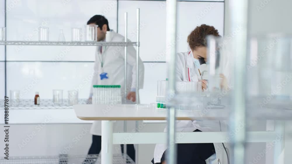 Research scientist working in laboratory, looking at sample under microscope. Research scientist working in laboratory, looking at sample under microscope.