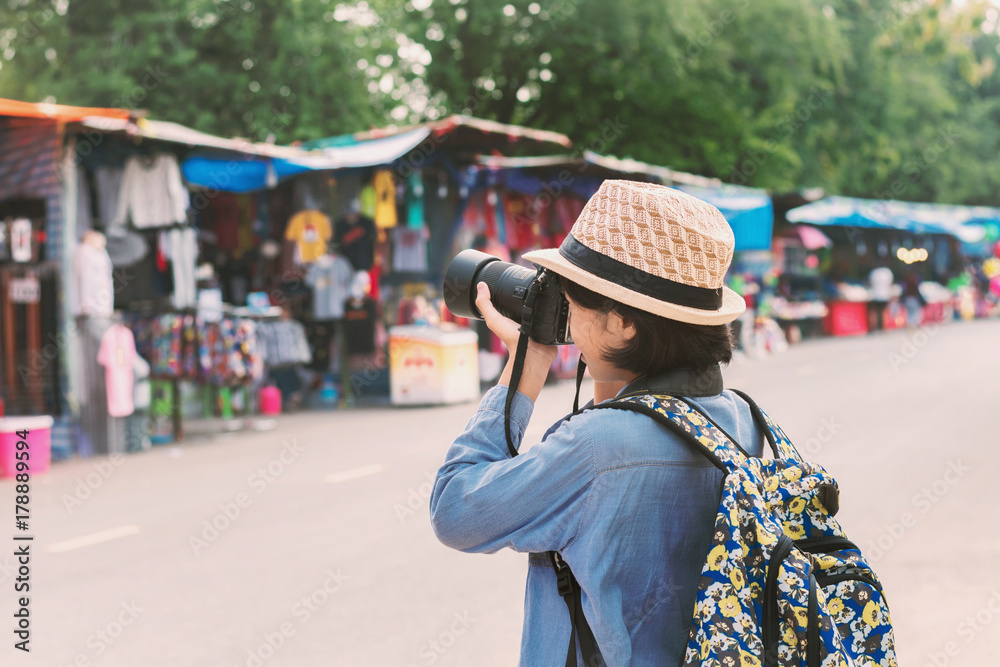 young asian woman traveler taking photo on street market