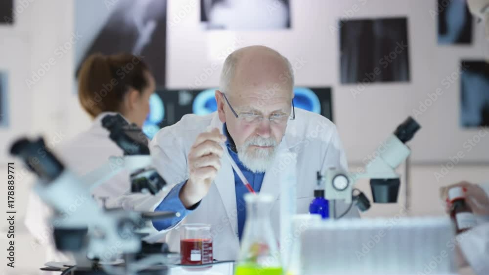 Scientific research team working in the lab, focus on man experimenting with chemicals Scientific research team working in the lab, focus on man experimenting with chemicals
