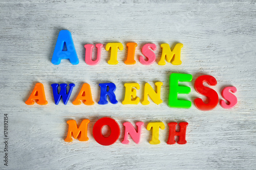 Text AUTISM AWARENESS MONTH on wooden background