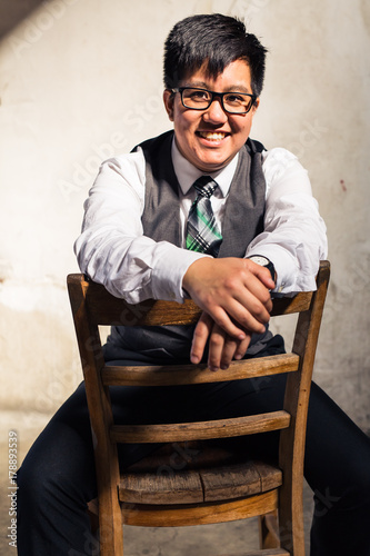 Young transgender man in formal clothing poses in a grungy urban location photo