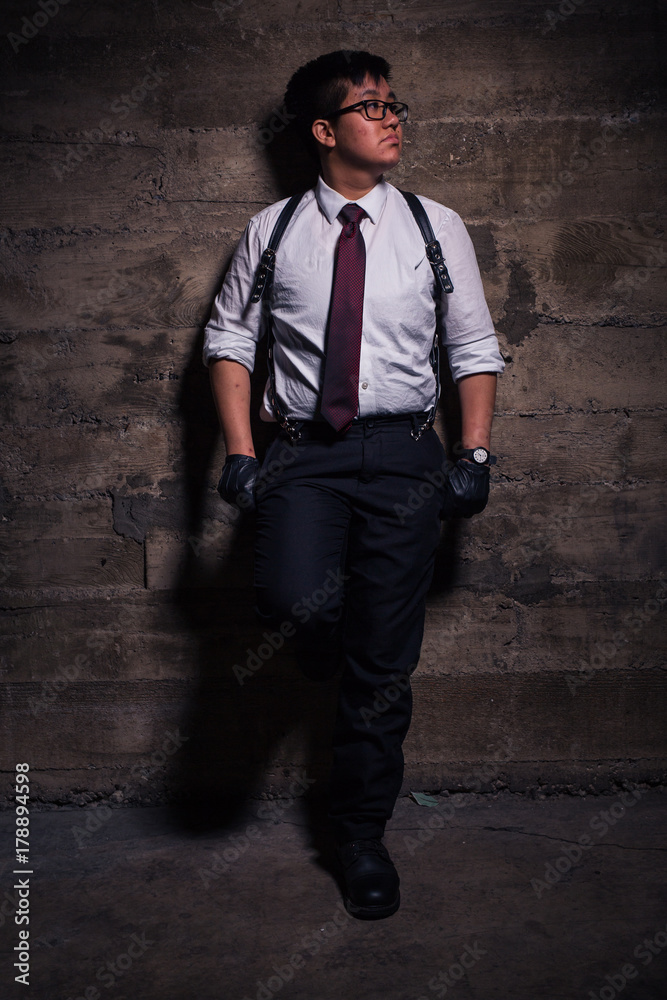 Young transgender man in semi formal clothing with a bondage style leather harness poses in a grungy urban location Young transgender man in semi formal clothing with a bondage style leather harness poses in a grungy urban location