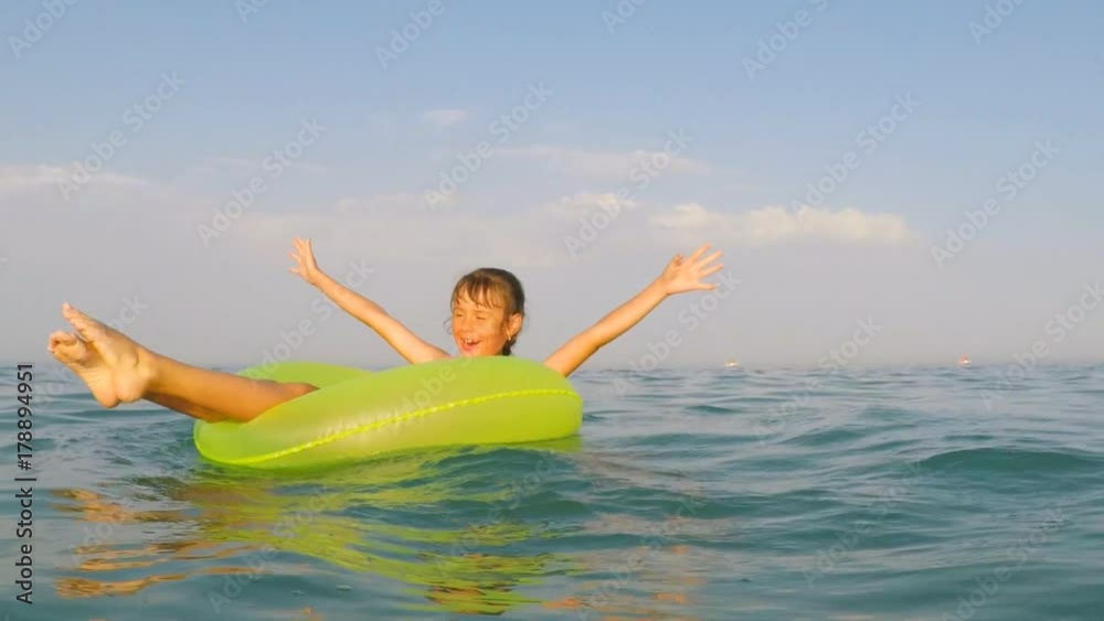A happy child is spinning on an inflatable circle in the water. A little girl is floating on an inflatable circle in the sea. A happy child is spinning on an inflatable circle in the water. A little girl is floating on an inflatable circle in the sea.