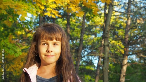 The face of a happy child. Little girl close-up in autumn park. photo