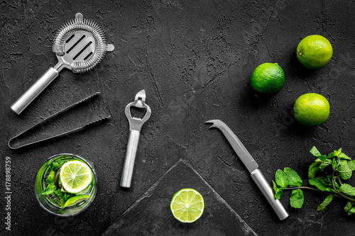 In the bar. Shake mojito. Lime, mint., barman tools on black background top view copyspace