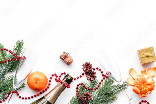 New year eve background. Spruce branch, glasses, champagne bottle, tangerines on white background top view copyspace
