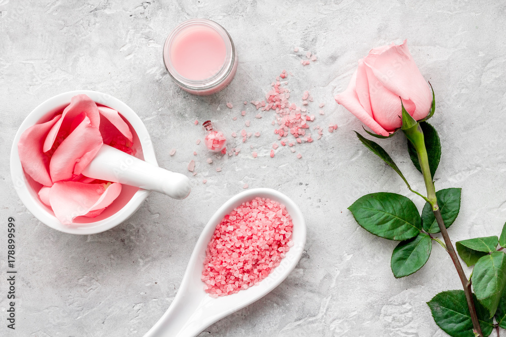 Products for skincare based on rose oil. Cream, lotion, spa salt on grey background top view Products for skincare based on rose oil. Cream, lotion, spa salt on grey background top view