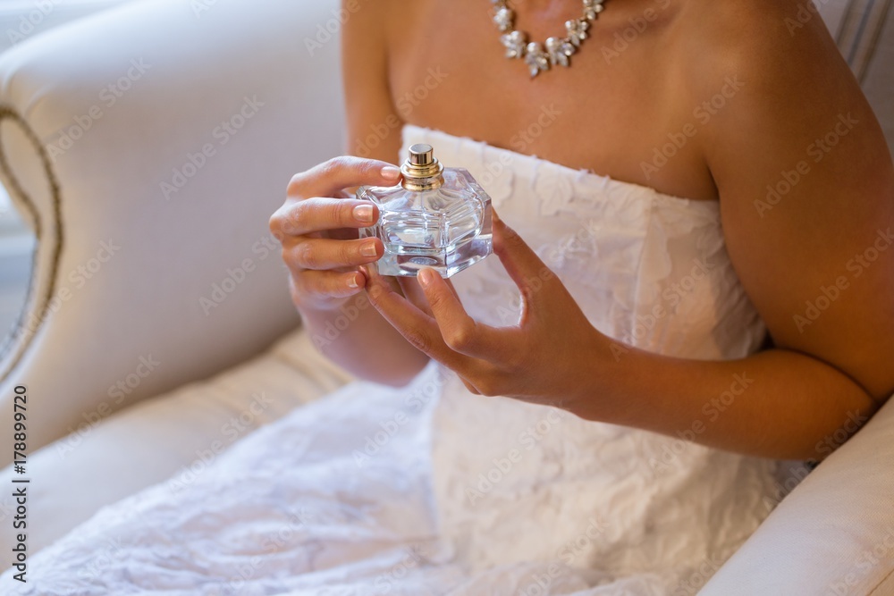 Midsection of bride holding perfume sprayer while sitting on Midsection of bride holding perfume sprayer while sitting on
