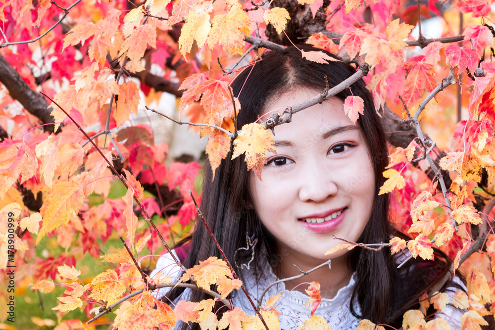 A young oriental girl is surrounded by autumn leaves