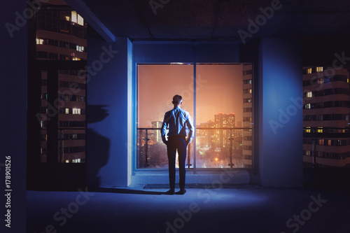 Office worker employee near big window night