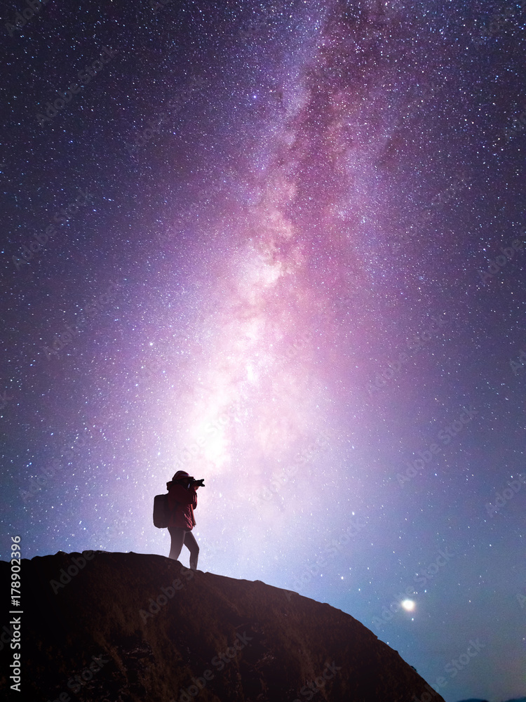 Fototapeta premium Silhouette of a camera girl who shooting a milky way