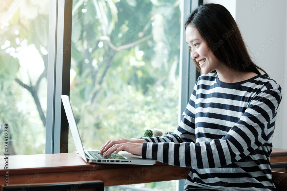 Young asian woman using laptop computer with smiling and happy face while sitting in cafe background, people and technology, lifestyles Young asian woman using laptop computer with smiling and happy face while sitting in cafe background, people and technology, lifestyles
