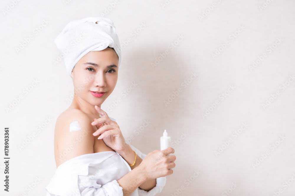 Beautiful girl in bath towel is applying cream on her shoulder. Beautiful girl in bath towel is applying cream on her shoulder.