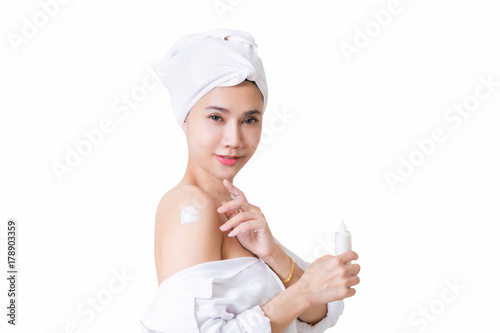 Beautiful girl in bath towel is applying cream on her shoulder. with clipping path