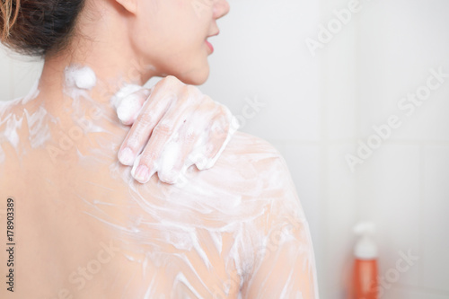 Woman taking a shower enjoying with foam bath.