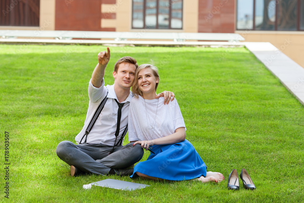 Fototapeta premium young couple sitting on the grass at the business center during a