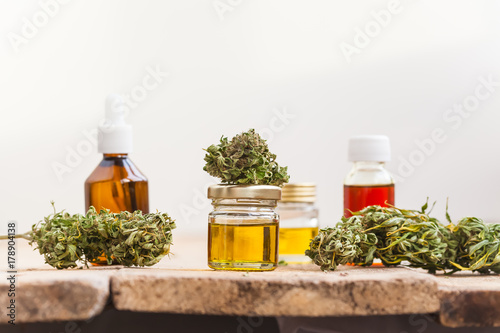 Fototapeta Naklejka Na Ścianę i Meble -  alternative medicine green leaves of medicinal cannabis with extract oil on a wooden table