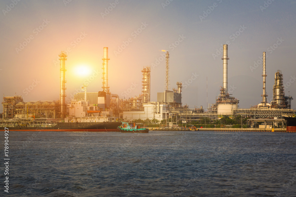 electric power generating factory, industry plant, chemical storage tanks and sunlight of sunset at evening near the river