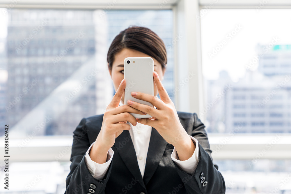 Fototapeta premium young businesswoman taking a picture with smart phone