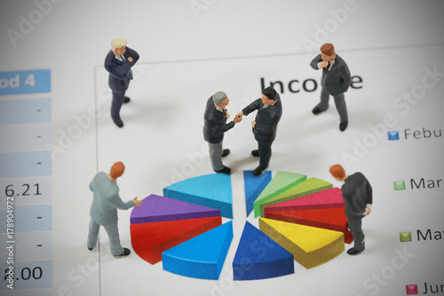 Top view selective focus of miniature businessman handshake on circle chart background as commitment and investment concept.