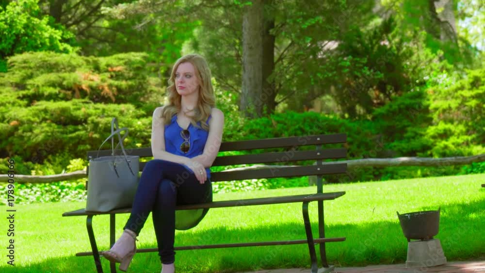 blond american women sitting on park bench looking around blond american women sitting on park bench looking around