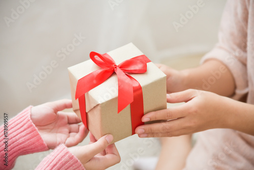 Asian woman hands giving a brown gift box. © eggeeggjiew