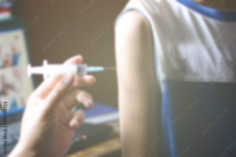 the blur of a doctor injecting medicine for the young asian boy the blur of a doctor injecting medicine for the young asian boy