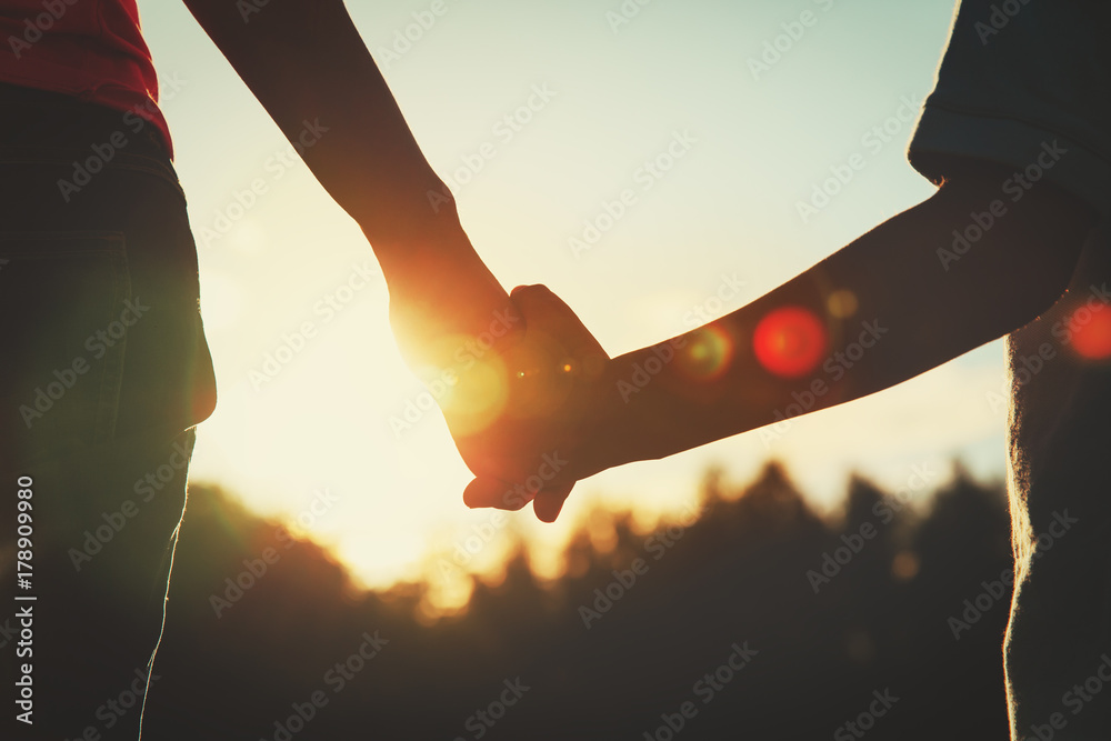 silhouette of parent and child holding hands at sunset