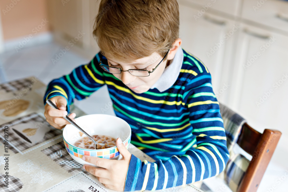Happy little blond kid boy eating cereals for breakfast or lunch. Healthy eating for children. Happy little blond kid boy eating cereals for breakfast or lunch. Healthy eating for children.