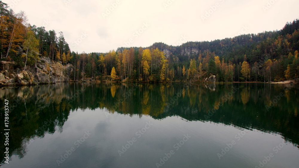 Piękne górskie jezioro przy wejściu do Skalnego Miasta w czeskim Adelsbach z jesiennymi kolorami drzew