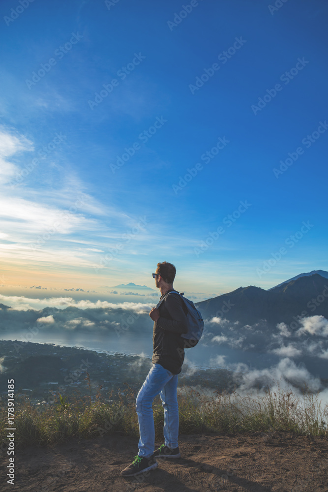 Man hiker looking to distant landscape from Mt. Batur, Bali, Indonesia.