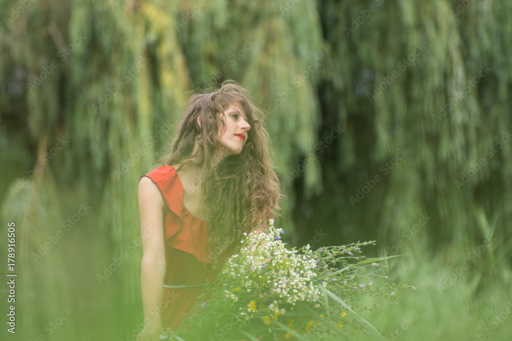 Beautiful young woman in red dress by the river water Beautiful young woman in red dress by the river water