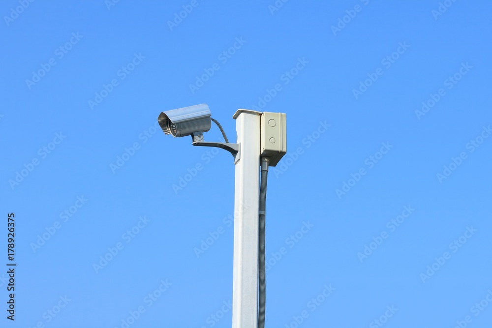 Closed circuit television camera on white steel pole with the background of blue sky. Closed circuit television camera on white steel pole with the background of blue sky.