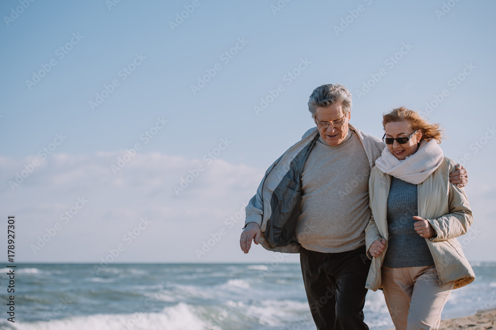 senior couple embracing and walking on seashore