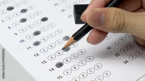 Student hand testing doing examination test by filling out answers bubbled and erasing the pencil mark to change the answer.