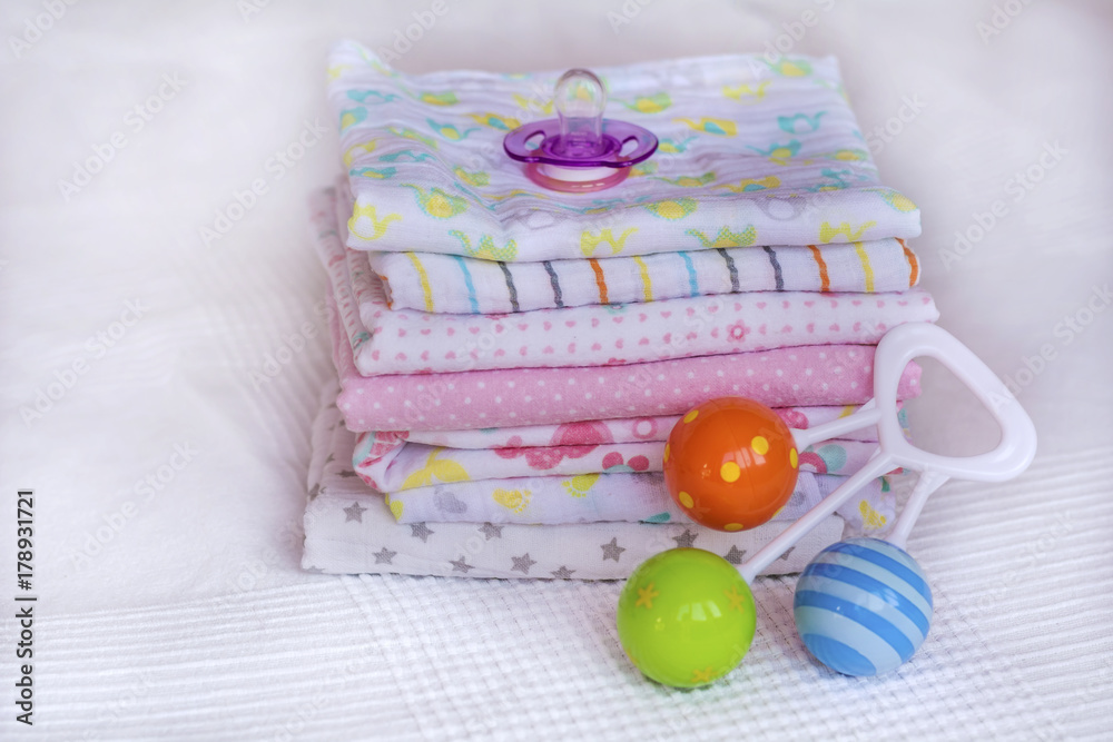 Stack of baby diapers and baby rattle Stack of baby diapers and baby rattle