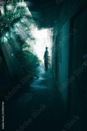 Perspective of man on the end of way in darkness with covering retro abandoned house © ApiFoto