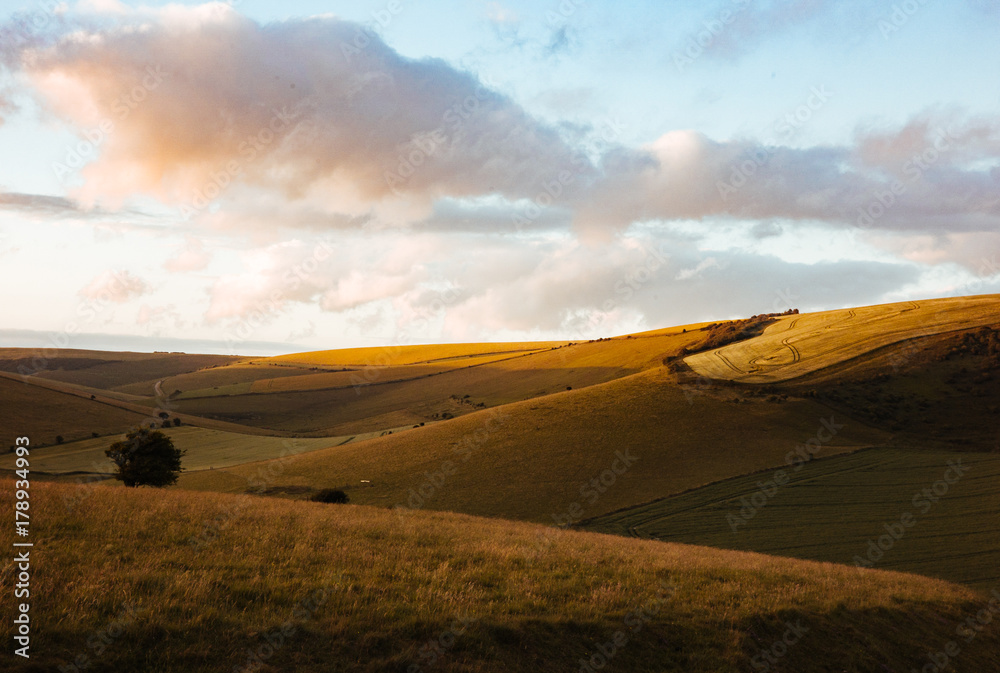 Obraz premium An ending sunset creates a colourful sky and textured valley in South Downs, England.